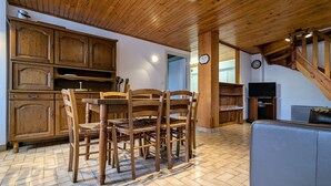 Un comedor de madera con una mesa, sillas, un televisor y una escalera.