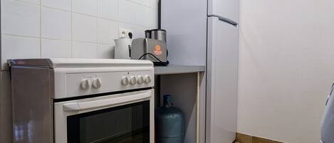 Une cuisine compacte équipée d’une cuisinière, d’un four, d’un réfrigérateur et d’un distributeur d’eau.