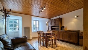 Una sala de estar acogedora con un sofá de cuero, una zona de comedor con sillas de madera, una cocina con armarios de madera y un techo de madera.