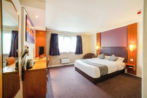 A hotel room with a bed, a desk with a kettle, a chair, a mirror, and a window with curtains. - OYO Lakeside Haydock Hotel ST Helens (St Helens)
