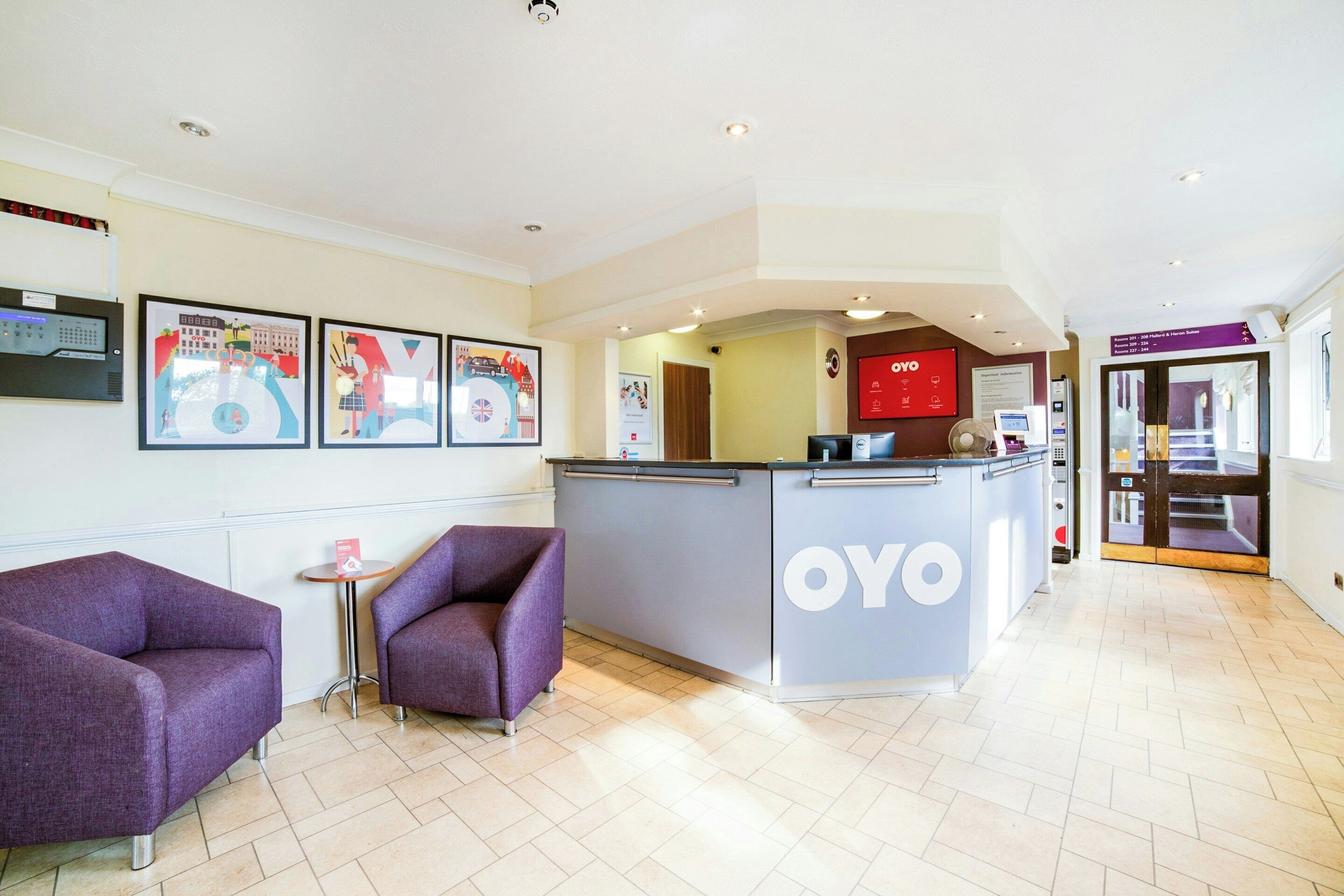 A reception area with a counter, two purple armchairs, and framed artwork on the wall.