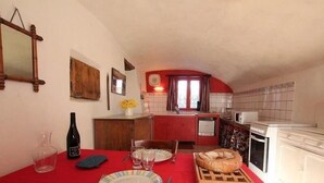 Un coin repas avec une nappe rouge, une miche de pain et une bouteille de vin.