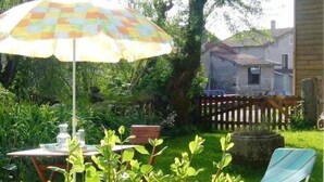 En terrasse med et bord, stole og en parasol, samt et træhegn.