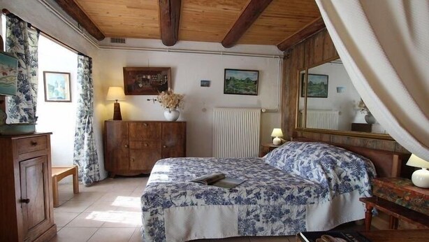 Une chambre à coucher avec un lit, une tête de lit en bois, une commode, un miroir et une fenêtre avec des rideaux.