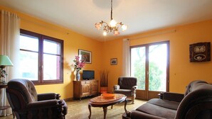 A living room with a fireplace, wooden furniture, a television, and a clock on the wall.