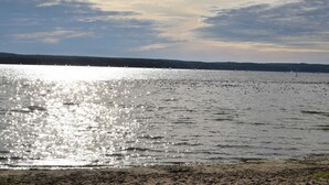 A calm lake with boats, a clear sky, and a distant shoreline.
