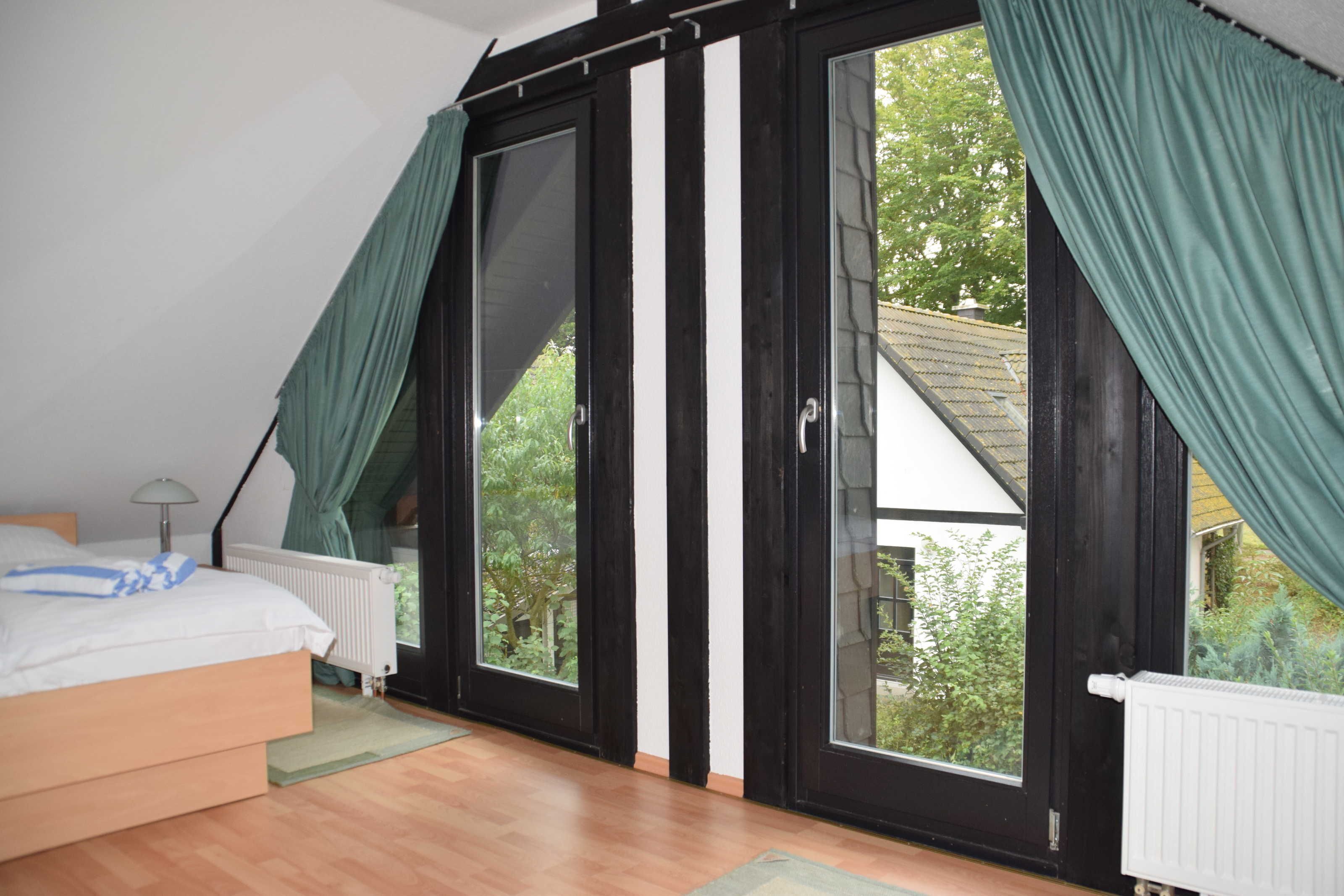 Quarto com cama, radiador e janela com cortinas.