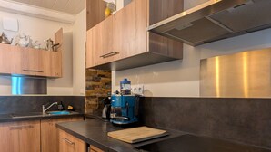 A modern kitchen with wooden cabinets, a stainless steel countertop, a coffee machine, and a built-in oven. - Apartment in the heart of Le Puy-en-Velay (Le Puy-en-Velay)