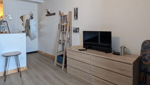 A modern living room with a flat-screen TV, wooden furniture, and a ladder bookshelf. - Apartment in the heart of Le Puy-en-Velay (Le Puy-en-Velay)