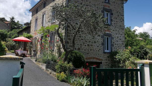 Un bâtiment en pierre, de style architectural traditionnel, doté d’un petit balcon et d’une porte surmontée d’une arche décorative.