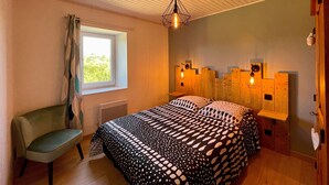 Ein Schlafzimmer mit Bett, Stuhl, Fenster, Holz-Kopfstütze und einer Decke mit Holzlatten.