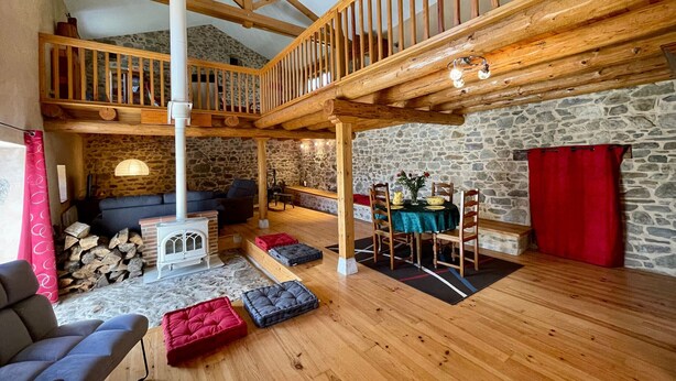 Ein gemütlicher Lofts-Wohnbereich mit Steinwand, Holzbalken, Kamin und Essbereich.