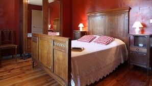 Une chambre à coucher avec un lit en bois, un miroir, deux tables de chevet avec des lampes et une chaise.