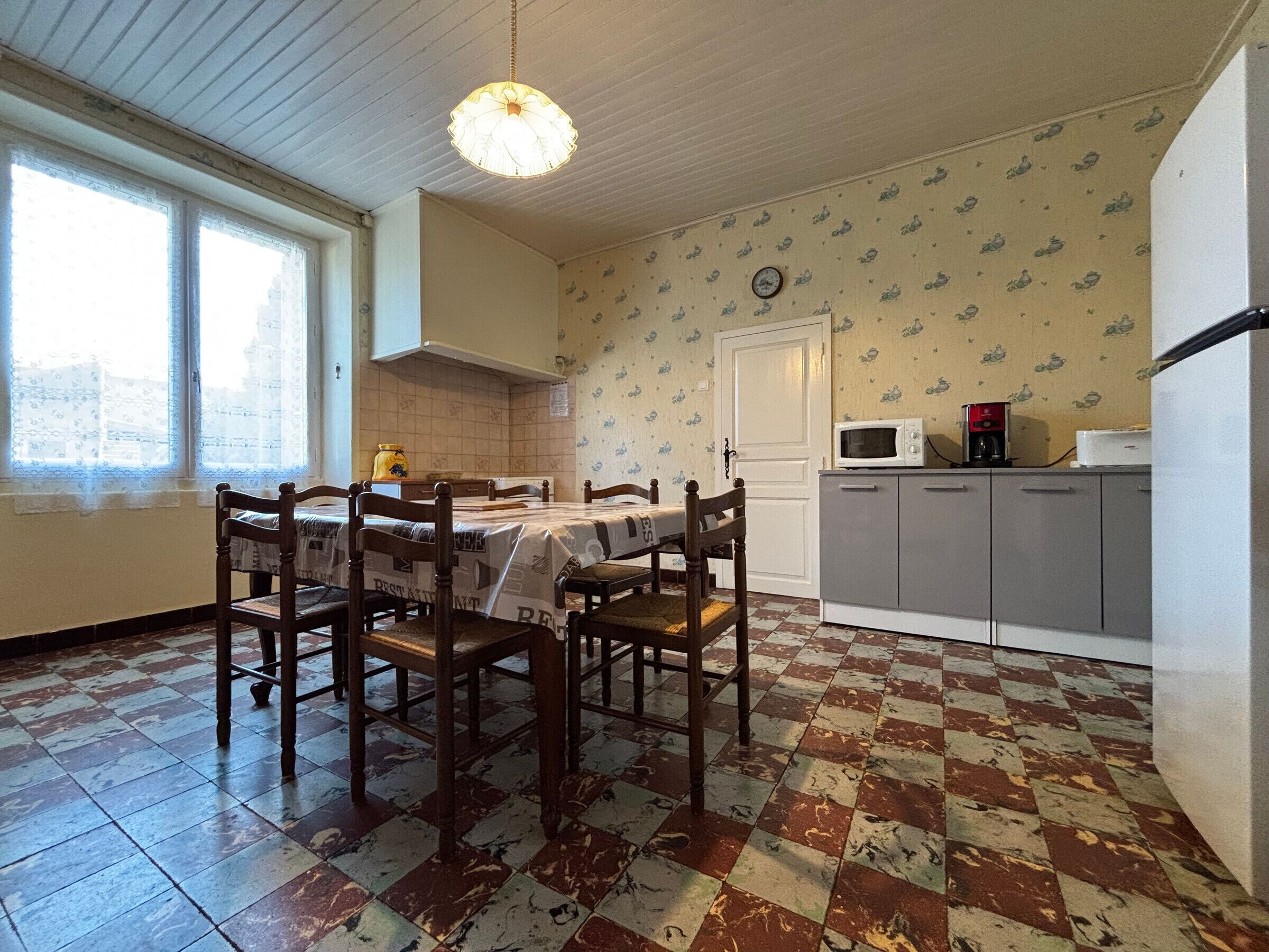 A kitchen with a dining table, chairs, a microwave, and a refrigerator.
