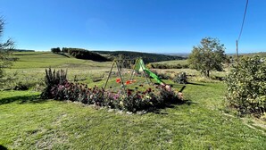 A grassy field with a swing set and a small garden with colorful flowers.