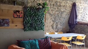Ein gemütlicher Raum mit einer Holzsofa, einem Tisch mit Stühlen und einer Steinwand.