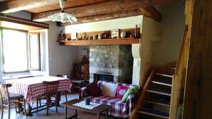 Ein gemütliches Wohnzimmer mit Kamin, eine Essecke mit Tisch und Stühlen sowie eine Treppe.