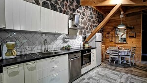 Een keuken met witte kastjes, een stenen muur en een houten plafond.