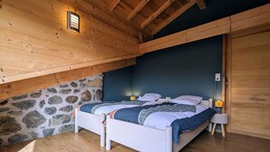Een slaapkamer met een houten plafond, een stenen muur en een bed met een sprei.