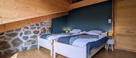 Ein Schlafzimmer mit Holzboden, Steinwand und einem Bett mit Patchworkdecke.