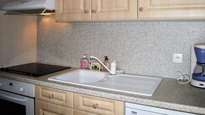 A kitchen with wooden cabinets, a granite countertop, a sink, a coffee maker, and a stove. - Cozy 2-Room Apartment for 6 with Terrace, Near Ski Slopes, Pet-Friendly (Bolquère-Pyrénées 2000)