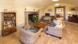 Un salón amplio con mobiliario de mimbre, chimenea y televisor.
