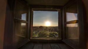 Una habitación con un ventanal grande que da a un paisaje al atardecer.