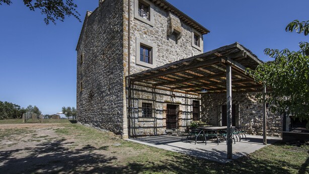 Un edificio de piedra con un patio cubierto y mesas al aire libre.