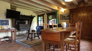 Ein rustikaler Essbereich mit Holztisch und -stühlen, einem Fernseher an der Wand und einem Kamin.