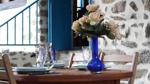 Ein Esstisch ist gedeckt mit Tellern, Besteck und einer Blumenvase.