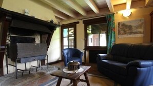 Ein gemütliches Wohnzimmer mit Kamin, blauem Sessel, einer Couch und einem Tisch mit einer Dekoration.