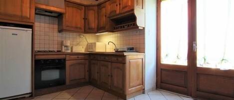 A kitchen with wooden cabinets, a white refrigerator, a microwave, and a sink.