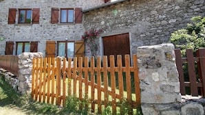 A stone building with wooden shutters and a wooden fence.