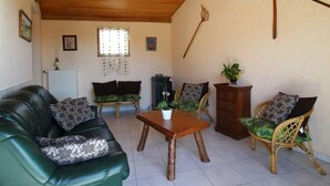 A living room with a green sofa, two armchairs, a wooden coffee table, and a radiator.