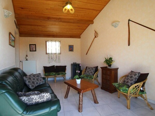 A living room with a green sofa, two armchairs, a wooden coffee table, and a radiator.