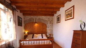 A bedroom with a wooden bed, a dresser, and stone walls.