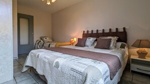 Un dormitorio con una cama grande, una mesita de noche, una lámpara y una puerta.