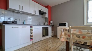 Una cocina compacta con armarios blancos, lavavajillas, horno y microondas.