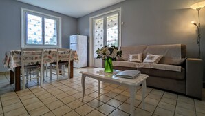Una sala de estar con comedor, un sofá, una mesa de centro y un refrigerador.