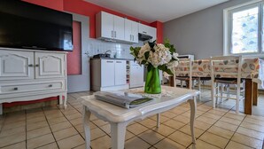 Una cocina moderna con armarios blancos, un comedor con mesa y sillas, y un ventanal con vistas.