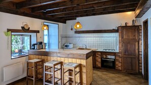 Une cuisine avec un plafond en bois, un grand îlot central doté de tabourets, un four à micro-ondes, un évier et une cuisinière.