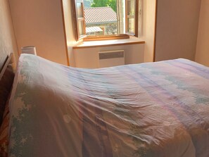 Une chambre à coucher avec un lit, une fenêtre et un radiateur.