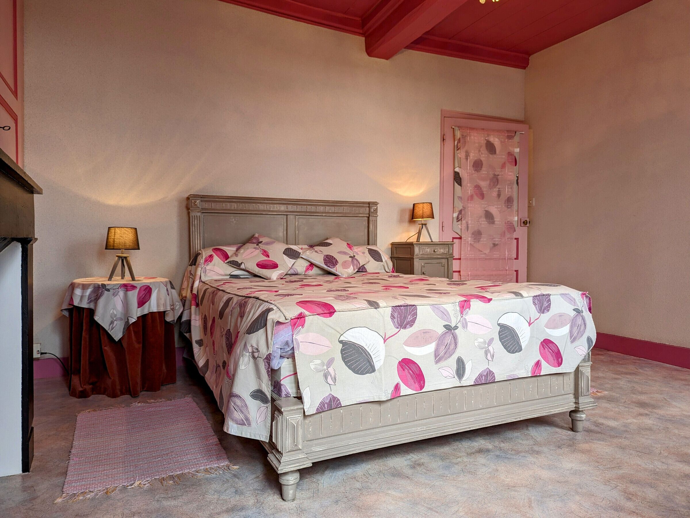 Ein Schlafzimmer mit einem Bett, zwei Nachttischen, einer Lampe, einer Tür und einem Teppich.