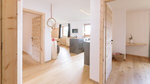 A modern interior with wooden floors, a kitchen with dark countertops, and a visible TV. - Holiday Home “Berg Wieserhof” with Mountain View, Balcony and Shared Garden (Aldein)