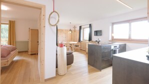 A modern kitchen with a central island, wooden flooring, and a dining area with a table and chairs. - Holiday Home “Berg Wieserhof” with Mountain View, Balcony and Shared Garden (Aldein)