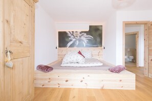 Un lit en bois avec une tête de lit, un tableau accroché au-dessus, et un plancher en bois.