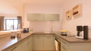 A modern kitchen with a built-in oven, a coffee maker, and a window with curtains. - Holiday Home “Wies Wieserhof” with Mountain View, Balcony and Shared Garden (Aldein)