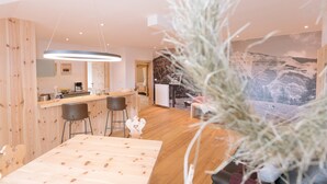 A modern kitchen with wooden accents, a bar area, and a large window with a mountain view. - Holiday Home “Wies Wieserhof” with Mountain View, Balcony and Shared Garden (Aldein)