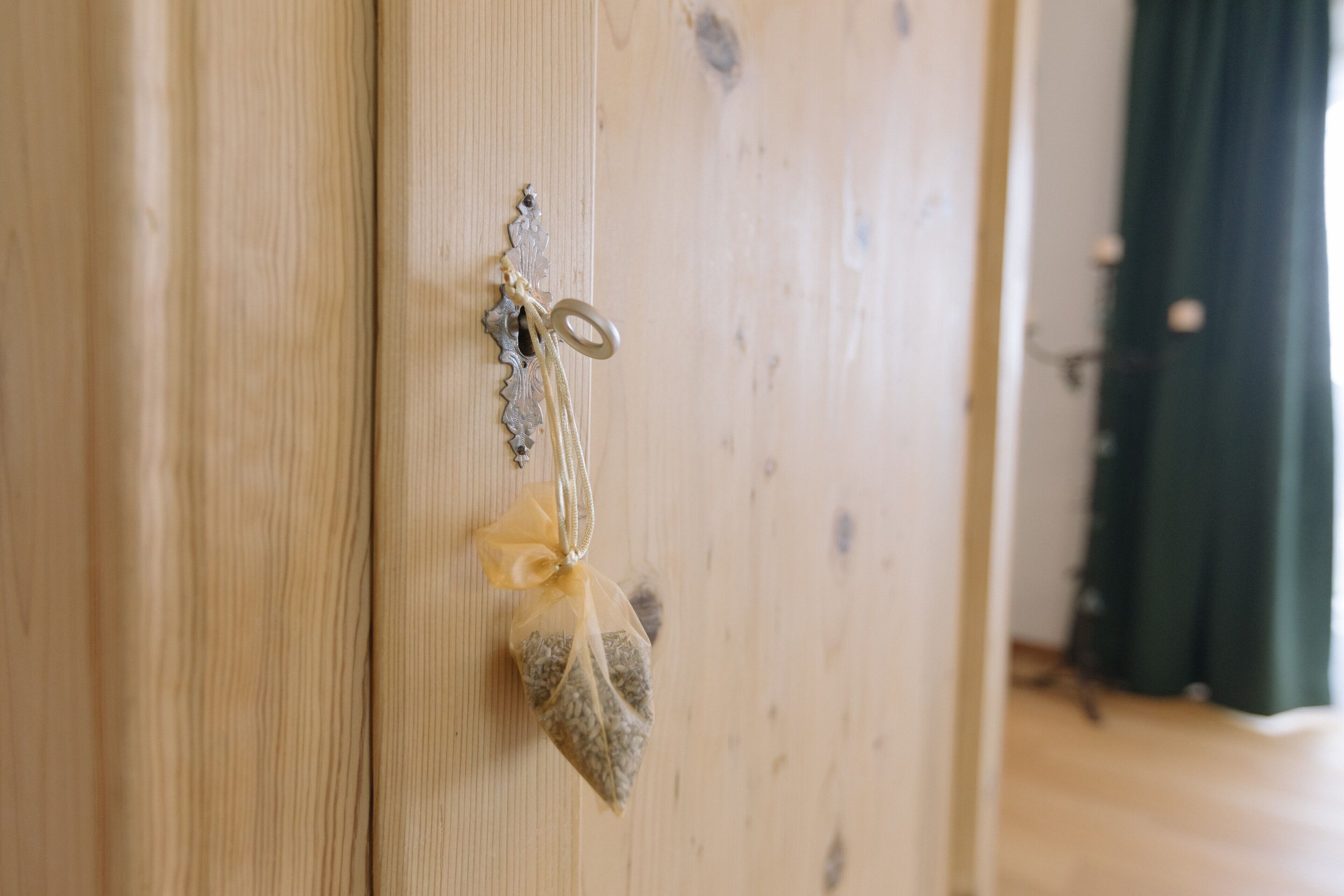 A wooden door with a keyhole and a small decorative item hanging on it.