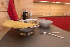A kitchen with wooden cabinets, a colander, a bowl, and a pair of forks on a countertop. - Holiday Home “Wold Wieserhof” with Mountain View, Balcony and Shared Garden (Aldein)